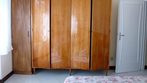 Een kamer met een houten garderobe, een witte deur en een kamerbreed tapijt met dessin.