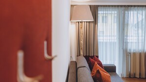 A living room with a sofa, a lamp, and a view through sheer curtains. - Alpine City Living - TOP 32, City center & balcony (Zell am See)