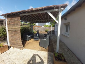A covered patio area with outdoor furniture, a pergola, and a gravel floor. - Vacation home near Chambord (Montlivault)