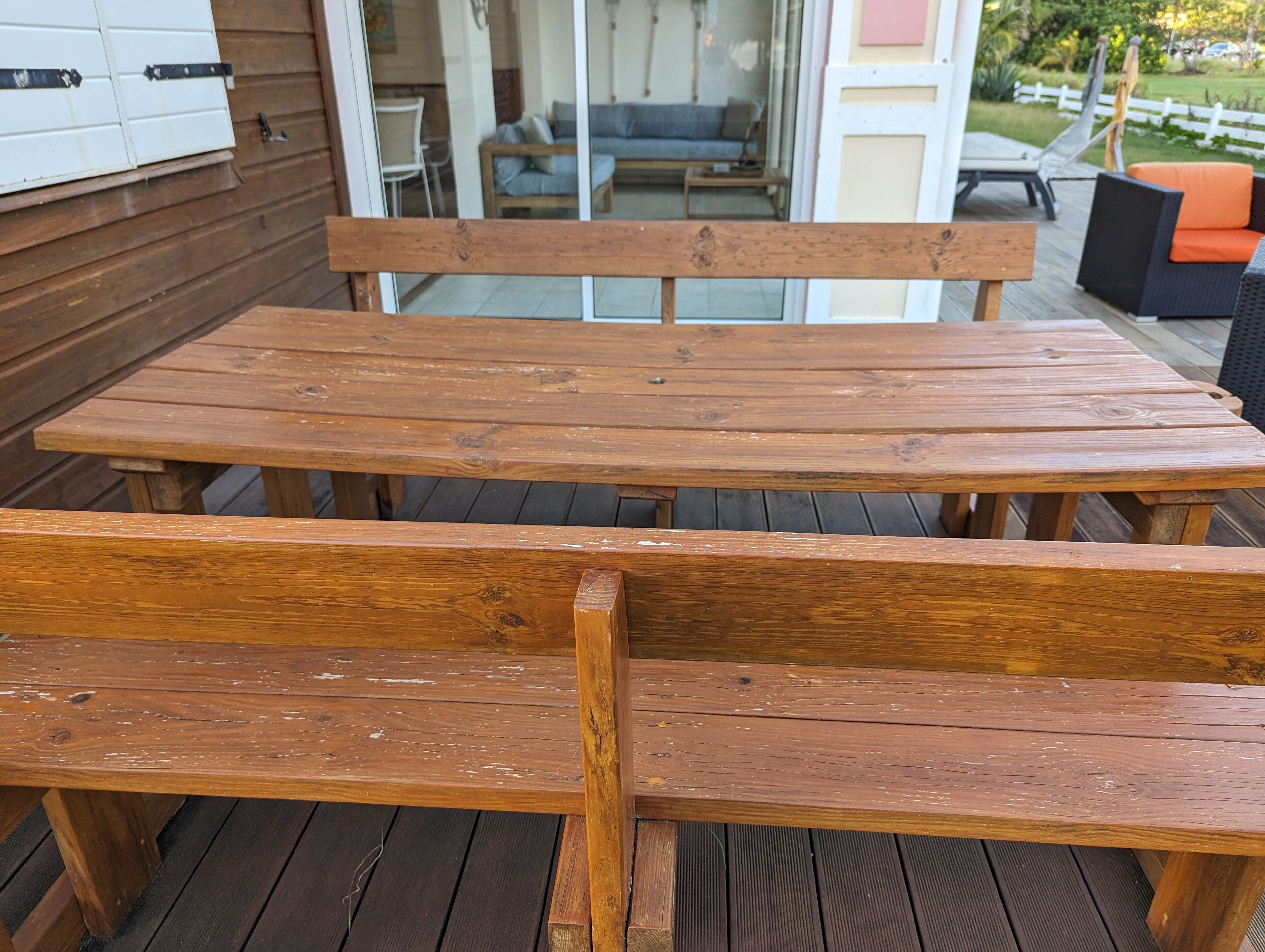 Um deck de madeira com uma mesa e bancos.