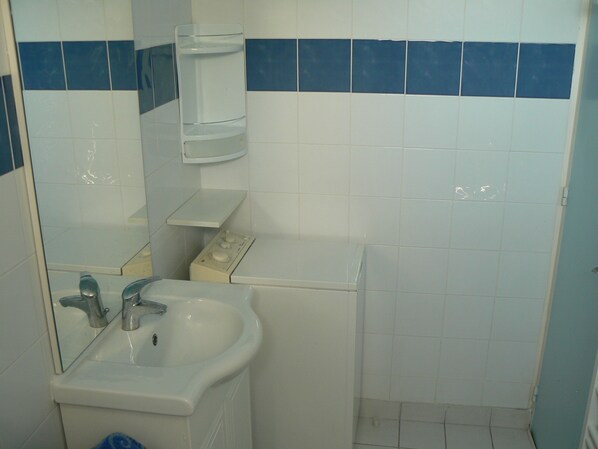 A bathroom with a sink, mirror, and a shelf with a glass container.