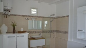 Un baño con cabina de ducha de vidrio, un lavabo blanco y un espejo encima.