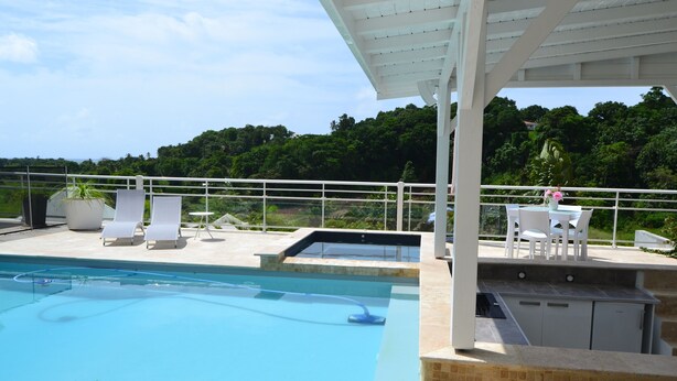Zona de piscina con sillones de descanso y un espacio cubierto para sentarse.