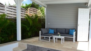 Un patio al aire libre con un sofá gris, una mesita y un armario blanco.