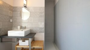Une salle de bain moderne avec un lavabo rectangulaire, un miroir et une étagère en bois en dessous.