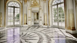 Ein prachtvoller Raum mit großen Bogenfenstern, aufwendigen Säulen und einem detailreichen Marmorboden.