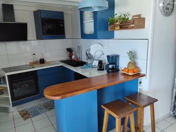 A modern kitchen with blue cabinets, a wooden countertop, a coffee maker, and a fruit bowl.