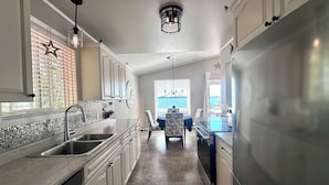A kitchen with a central island, a dining area with a table and chairs, and a view of the outdoors.