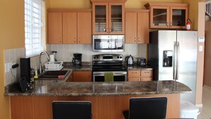 Una cocina con armarios de madera, un refrigerador de acero inoxidable, un microondas y una estufa.