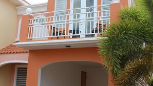 Un edificio de dos pisos con balcón, garaje y un pequeño jardín.