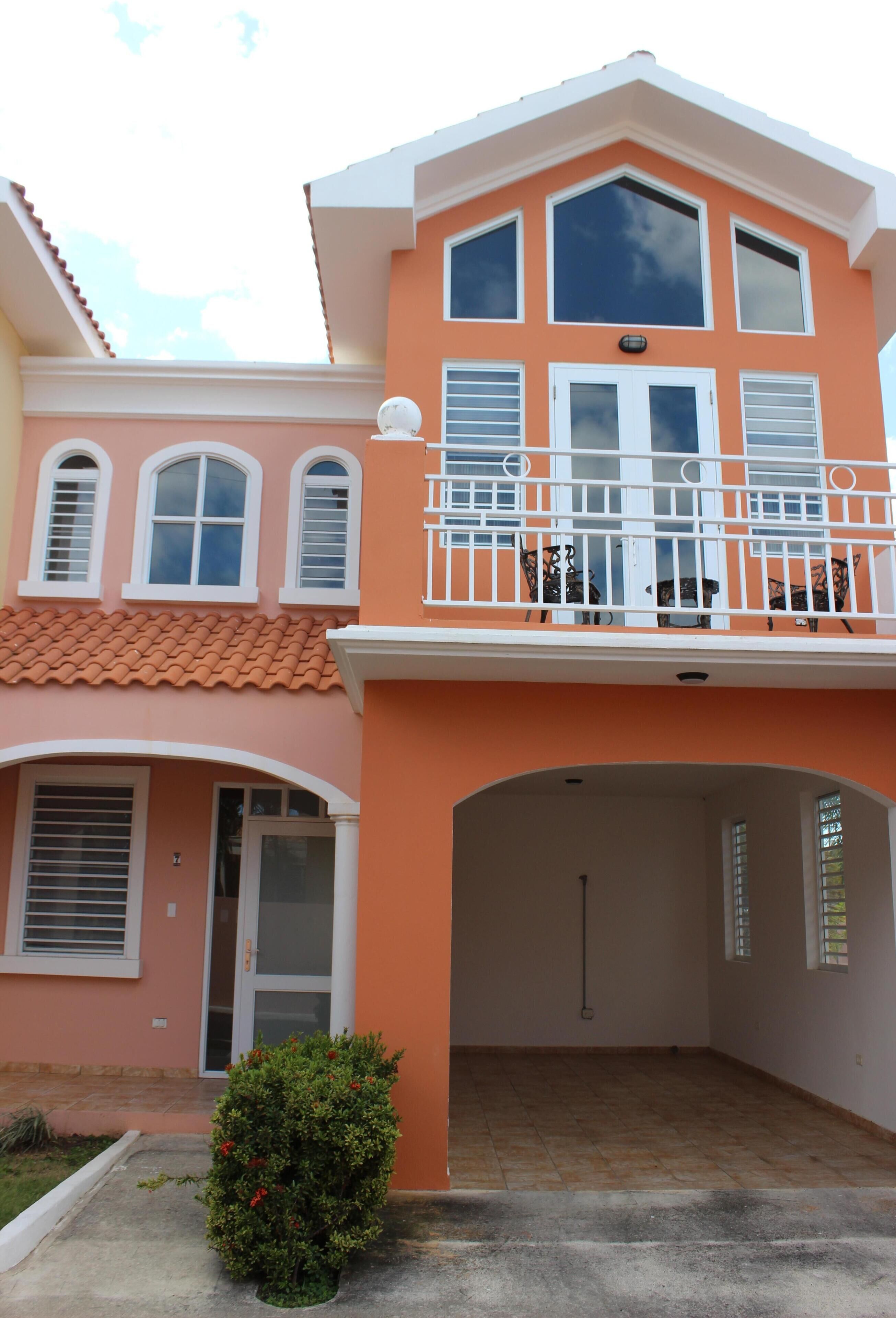 A two-story house with a balcony, a garage, and a small garden.