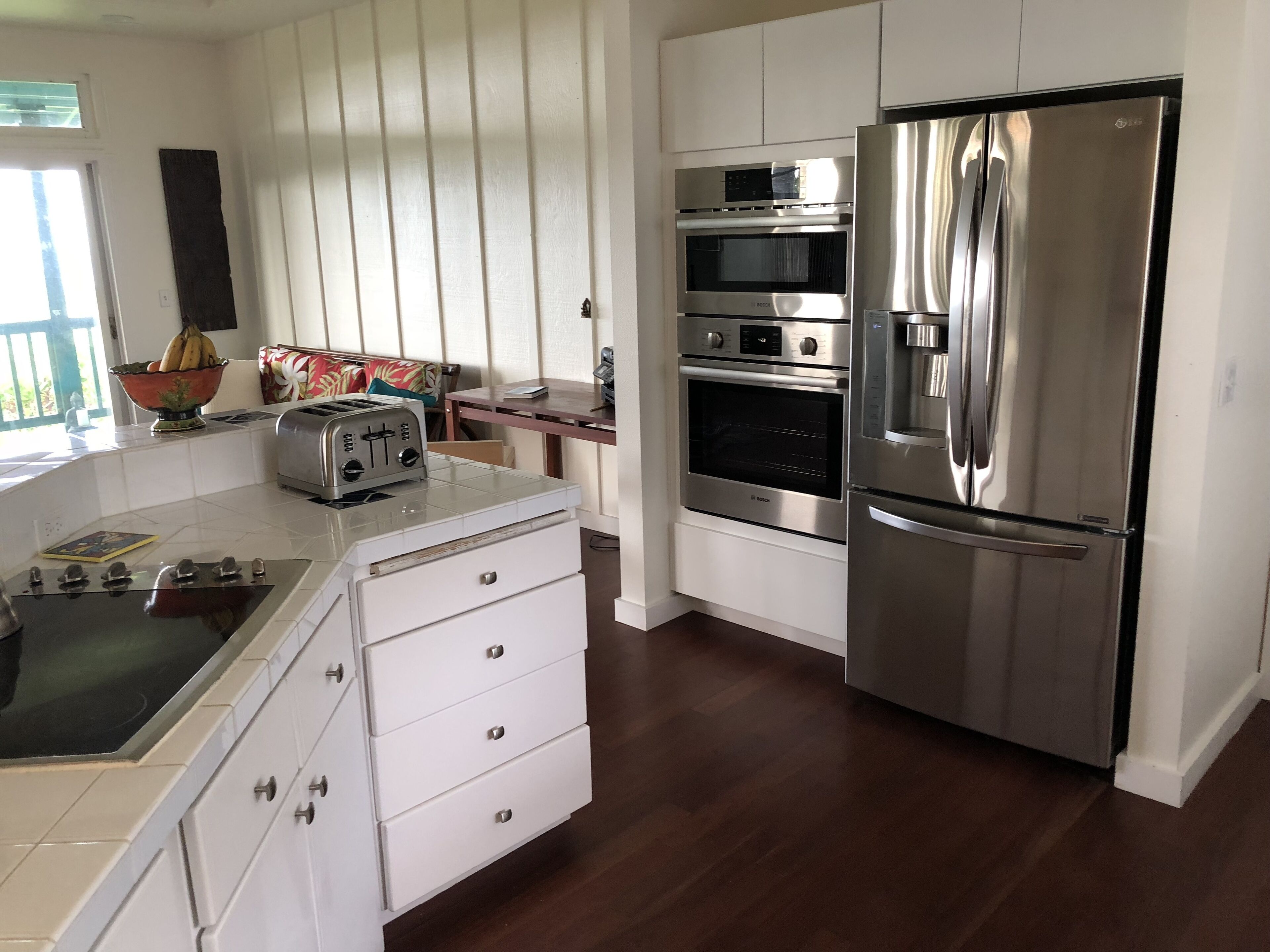 A modern kitchen with white cabinets, a stainless steel refrigerator, a built-in oven, and a toaster.