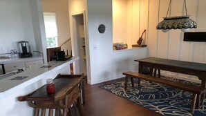A kitchen with a wooden bench and table, a hanging light fixture, and a patterned rug.
