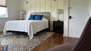 A bedroom with a bed, bedside tables, a nightstand, a chair, a window, and a door.