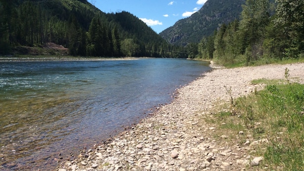 Un río de aguas claras, rodeado de colinas boscosas y una costa rocosa.