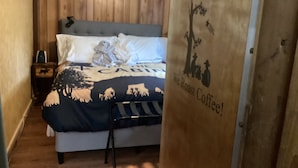 Un dormitorio con una cama, una mesita de noche y una pared de madera. Hay un cartel en la pared que dice "Mollana Coffee Traders We Roast Coffee!".