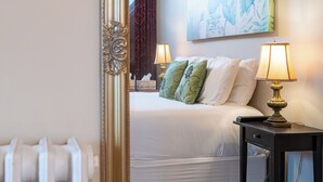 Une chambre d’hôtel avec un lit, des lampes de chevet, un tableau au mur et un radiateur.