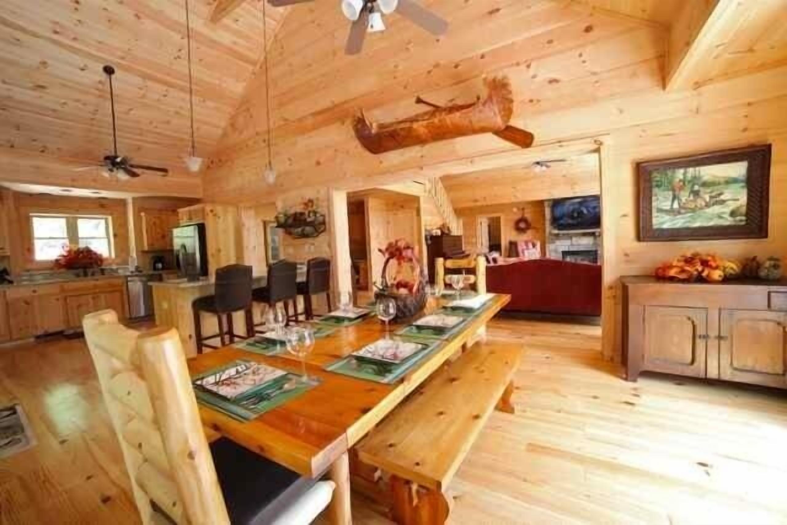 A wooden cabin interior with a dining area, kitchen, and living space.