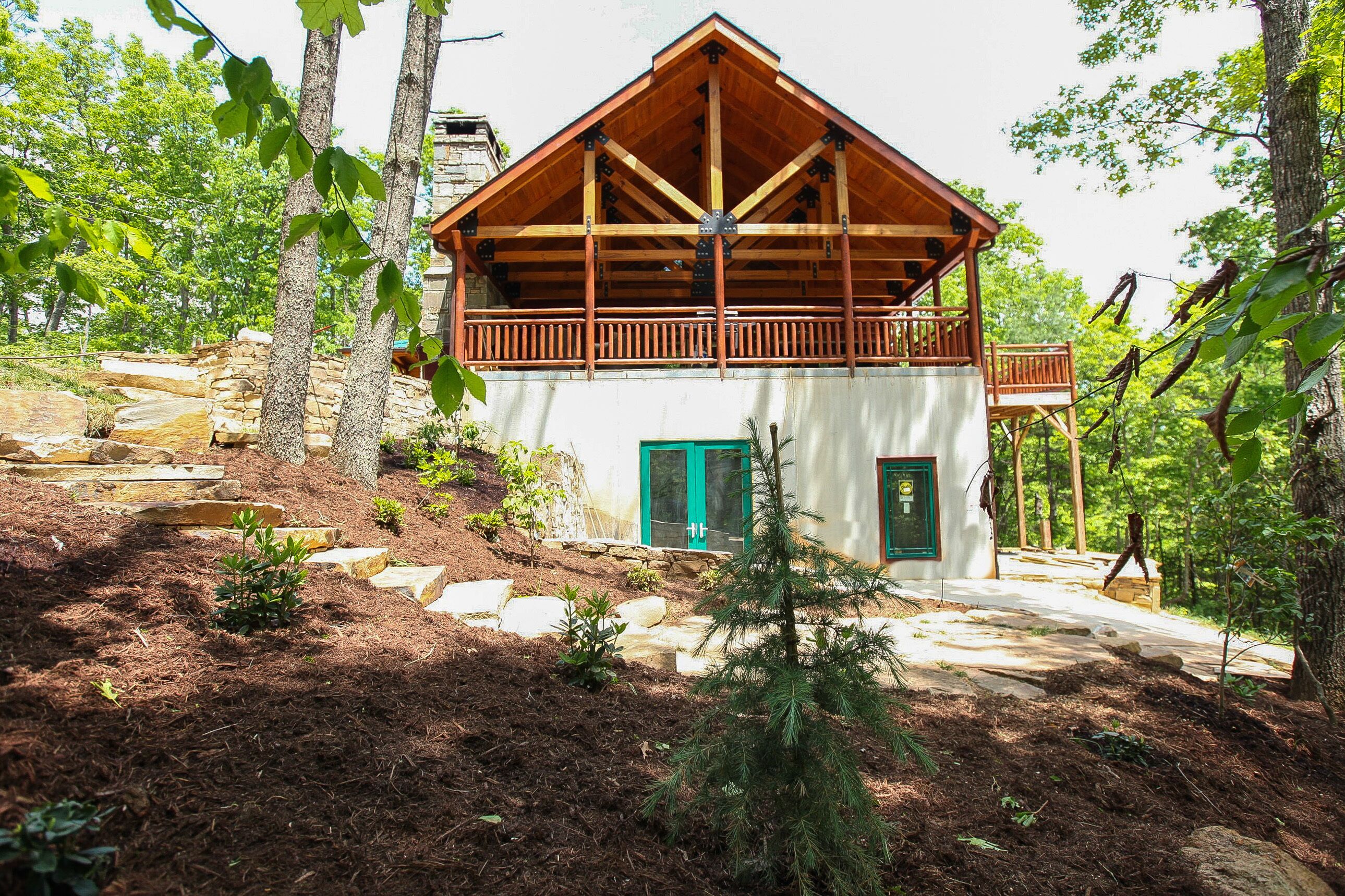 Una cabaña con terraza de madera, balcón y un sendero de piedra que conduce a la entrada.