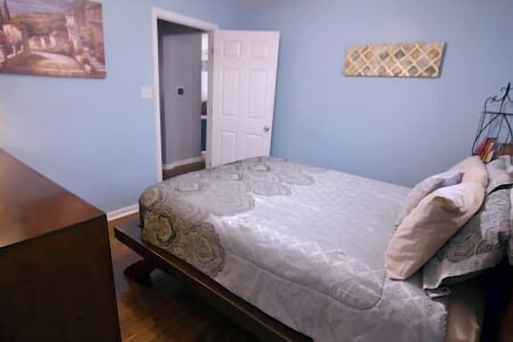 A bedroom with a bed, a door, and a wall-mounted shelf.