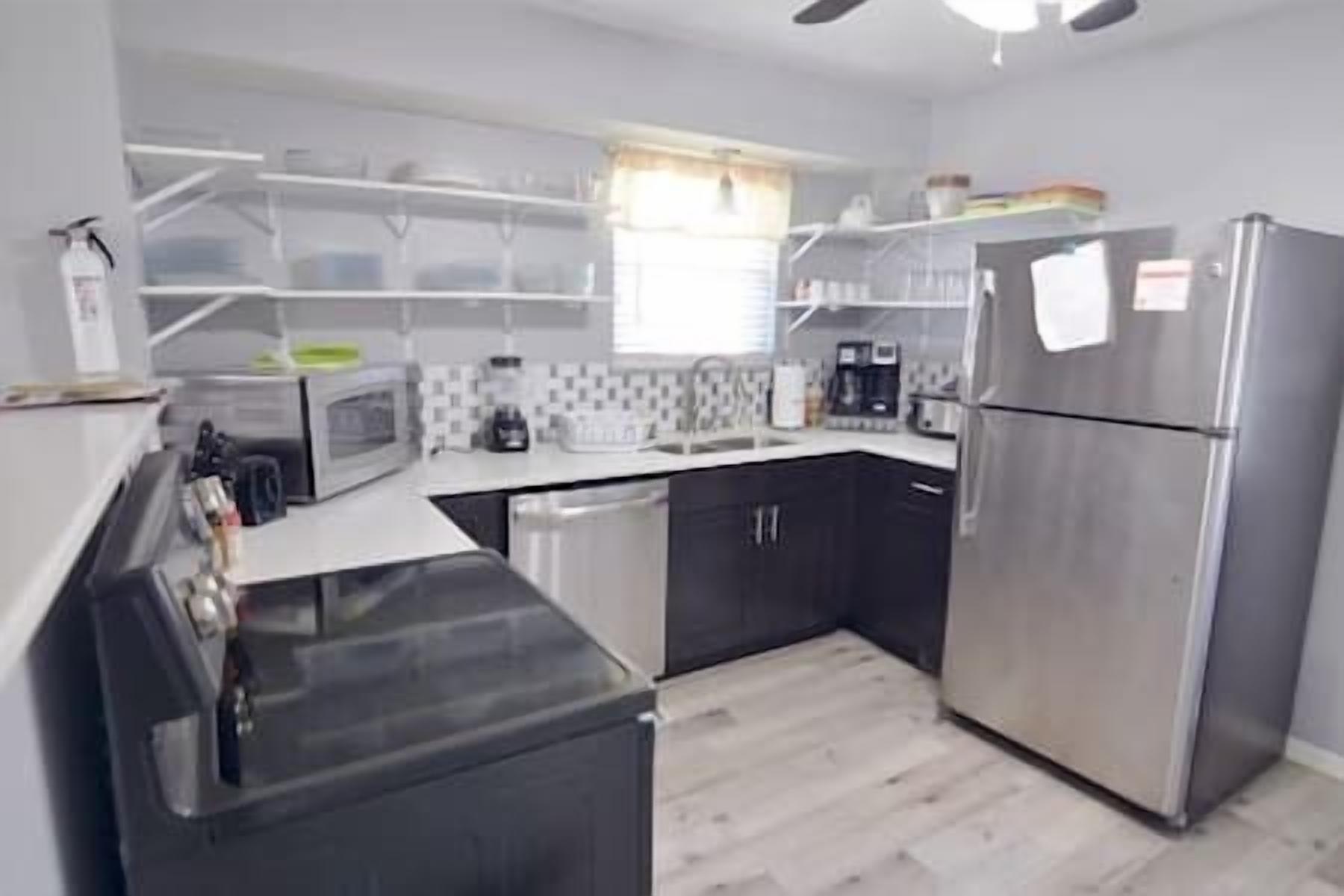 Una cucina moderna con mobili neri, un frigorifero in acciaio inossidabile, un forno a microonde e una macchina da caffè.