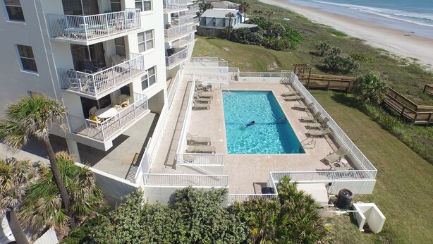 Ett hotell med en pool på taket, flera balkonger och utsikt över stranden.