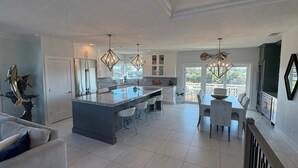 Una cocina amplia con una isla central, muebles de cocina blancos e iluminación colgante.