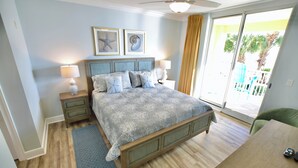 Quarto com cama, duas mesas de cabeceira, um criado-mudo, uma escrivaninha e uma cadeira.