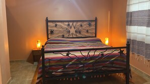 A bedroom with a bed, a ceiling fan, a window, and a nightstand with a lamp.