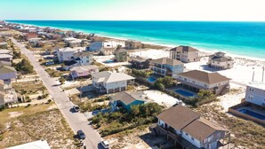 An aerial view of a coastal residential area with houses, a road, and a beach. - Beautiful Cozy Beach Cottage, 1 block to beach, west of hotels, easy access (Pensacola)