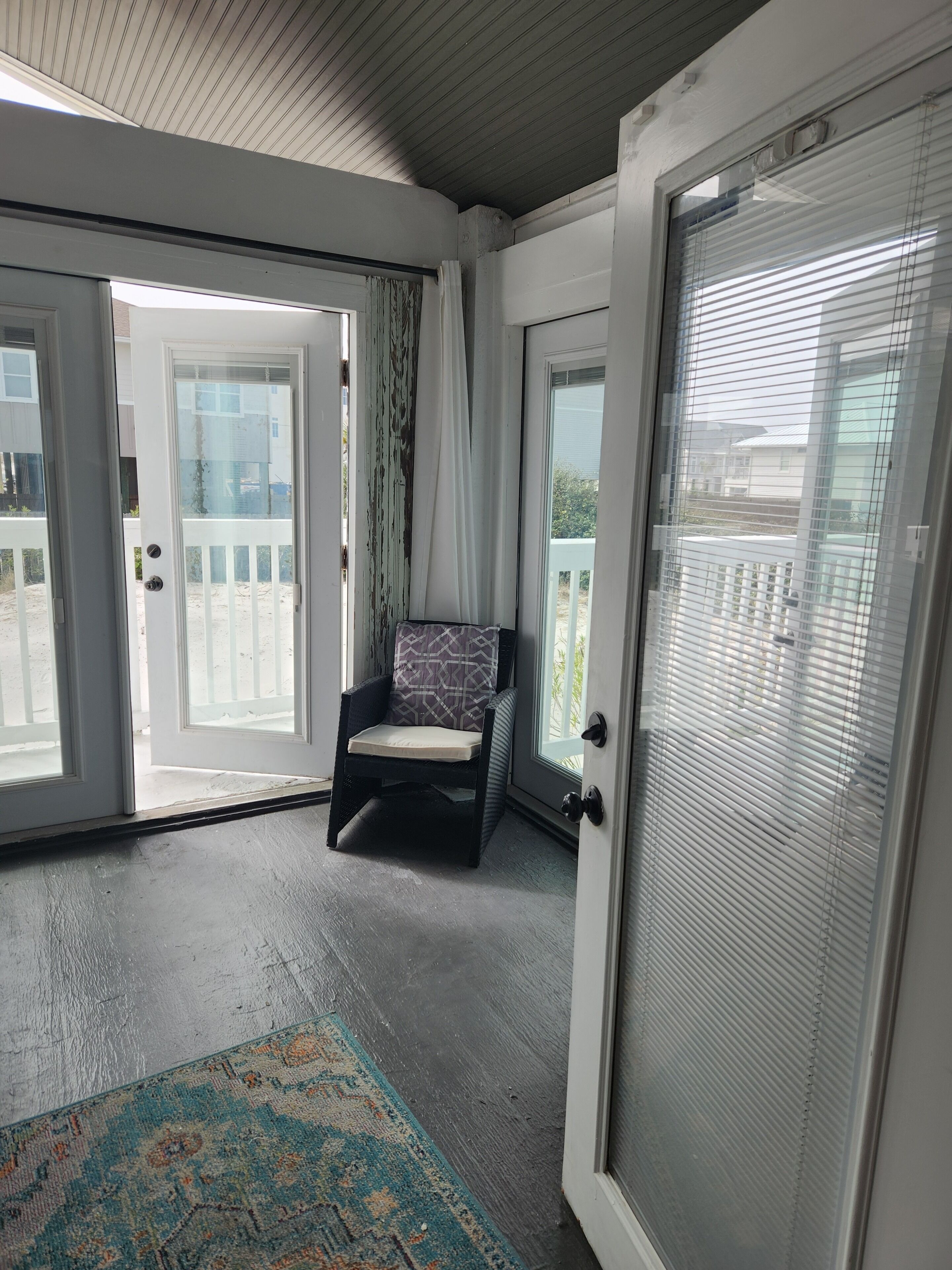 Een kamer met een schuifdeur naar een balkon, een comfortabele stoel en een kamerkleed met dessin.