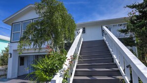 A two-story building with a staircase leading to the entrance. - Beautiful Cozy Beach Cottage, 1 block to beach, west of hotels, easy access (Pensacola)