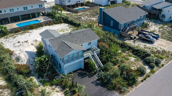 An aerial view of a coastal residential area with houses, a swimming pool, and a sandy beach. - Beautiful Cozy Beach Cottage, 1 block to beach, west of hotels, easy access (Pensacola)