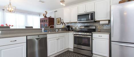 A modern kitchen with white cabinetry, stainless steel appliances, and a patterned rug.