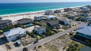 A coastal residential area with houses, a road, and a beach in the background. - Beautiful Cozy Beach Cottage, 1 block to beach, west of hotels, easy access (Pensacola)