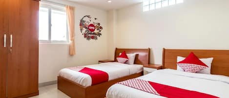 A hotel room with two beds, a wardrobe, a window with curtains, and a wall decoration.
