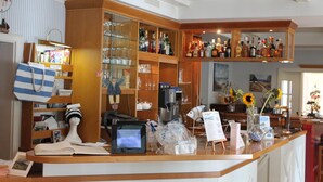Uma área de bar com prateleiras de garrafas, um caixa e um monitor de computador.