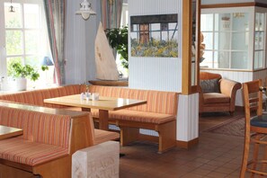 A cozy interior with striped upholstered seating, a wooden table, and a sailboat decoration.