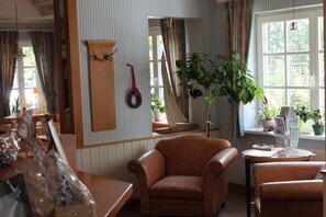 A room with a brown leather armchair, a wooden cabinet, a mirror, and a window with curtains.