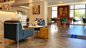 A modern hotel lobby with a bar area, seating arrangements, and large windows. - Oasis Hotel (Barcelona)