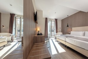 Una habitación de hotel moderna con una cama, dos sillones, un escritorio y un ventanal grande.