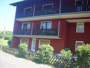 Punainen, useita kerroksia sisältävä rakennus, jossa on parvekkeita ja ikkunoita.