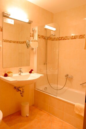 A bathroom with a sink, mirror, shower, and toilet. - Hotel an der Ilse (Lemgo)