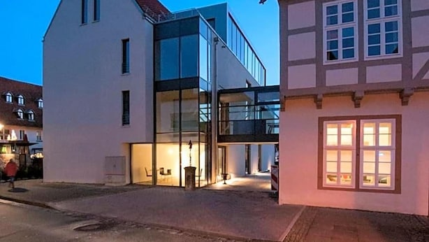 Un bâtiment moderne à la façade en verre et un bâtiment traditionnel doté d’un toit en tuiles.