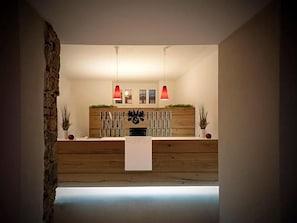 A reception area with a wooden reception desk, two red pendant lights, and a stone wall on the left.