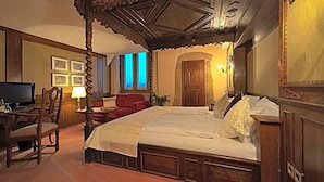 Une chambre traditionnelle avec un lit à baldaquin, une télévision et un bureau avec une chaise.
