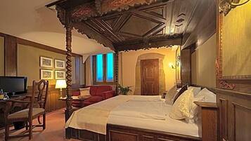 Ein traditionell eingerichtetes Zimmer mit einem Himmelbett, einem Fernseher und einem Schreibtisch mit Stuhl.