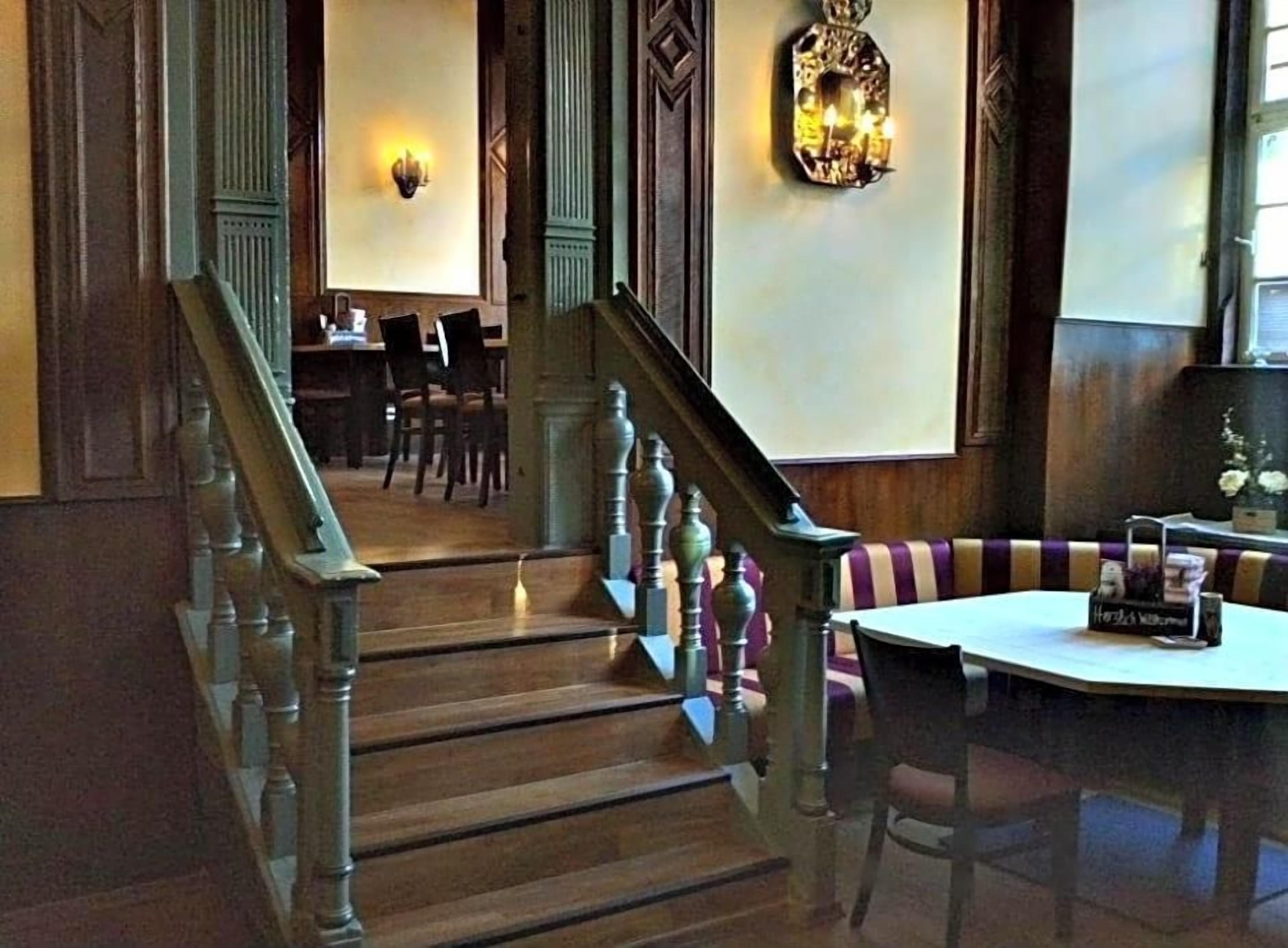 Eine Treppe mit hölzernen Geländern führt zu einem Essbereich mit einem runden Tisch und Stühlen.