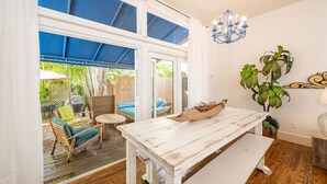Ein Zimmer mit einem weißen Tisch, blau gerahmten Fenstern, einer Kristallleuchtre und einer Pflanze.