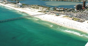 Vista aérea de una zona costera con playa, un puente y un edificio alto señalado como 472 Ft. Pickens Rd.